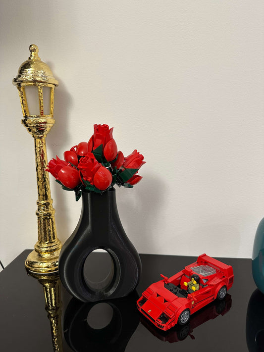 Design italiano: vaso tondo in PLA con fiori rossi e auto giocattolo, pop art per un interior design cool.