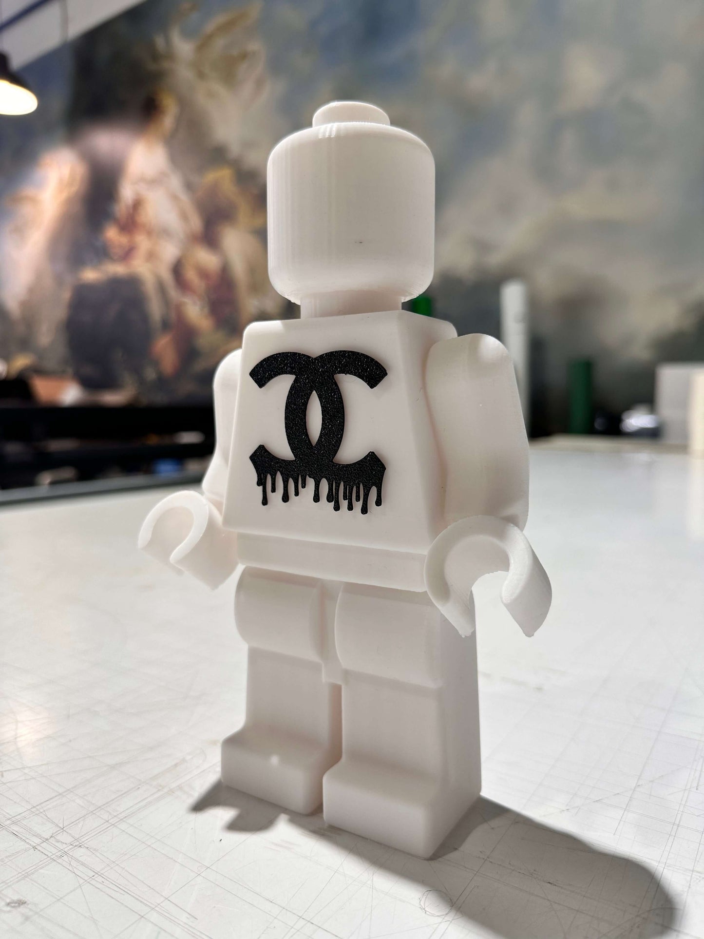 Mini Lego figure in white with a black dripping logo, perfect for pop art decoration and customizable designs.