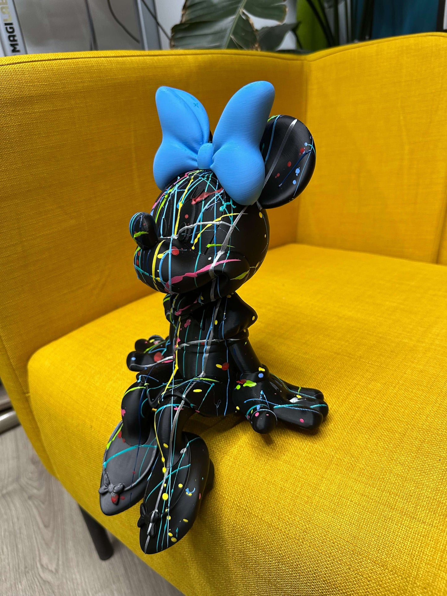 Minnie Mouse pop art statue in contemporary design, featuring colorful splatter on a black background.