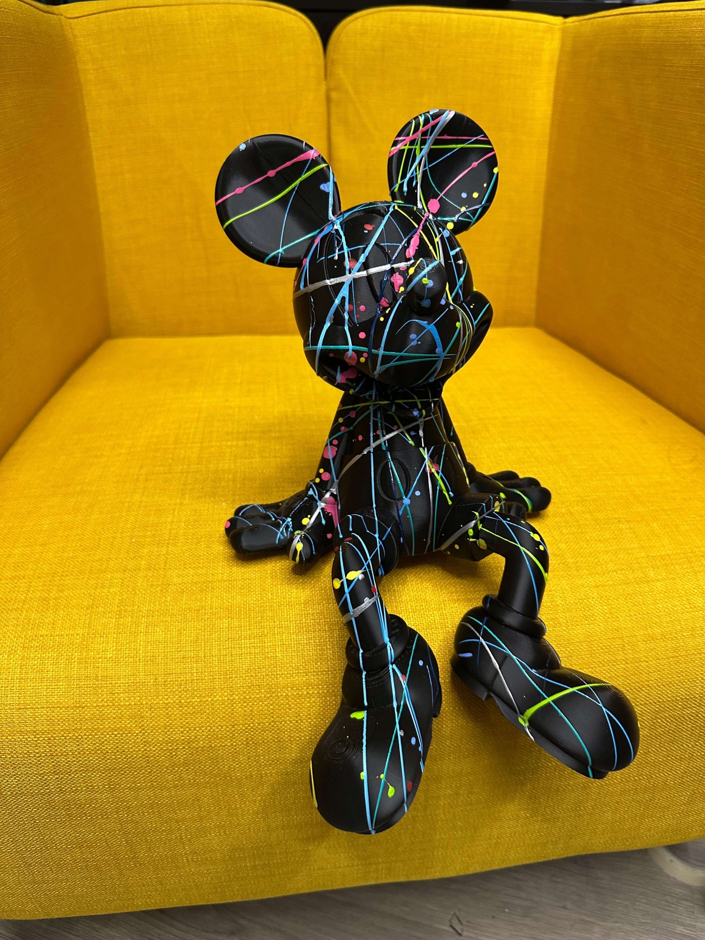 Minnie Mouse Pop Art statue in vibrant colors on a yellow chair, ideal for contemporary interior design.