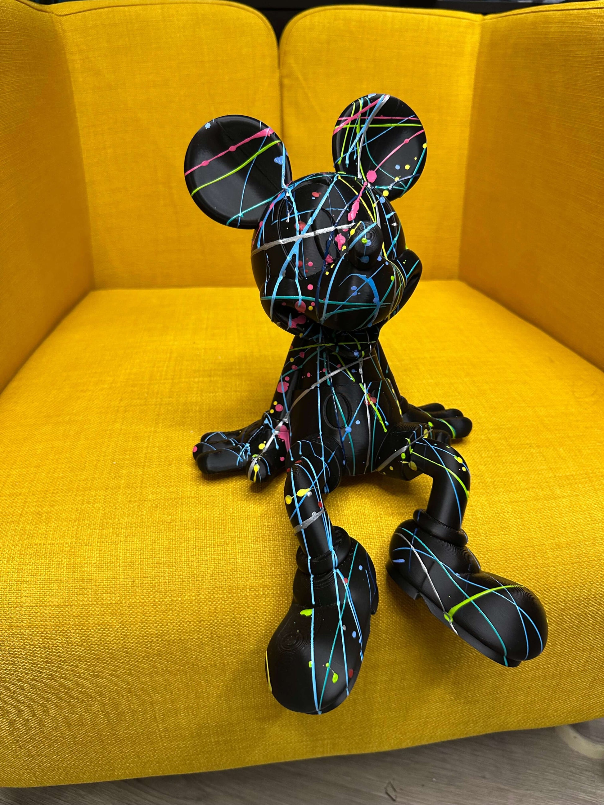 Minnie Mouse Pop Art statue in vibrant colors on a yellow chair, ideal for contemporary interior design.